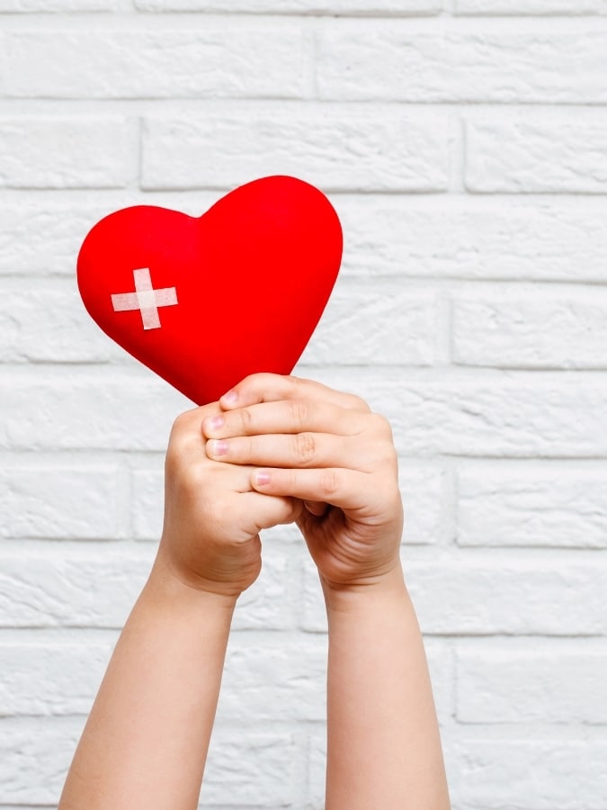 Prévention santé – enfant tenant un cœur avec croix médicale